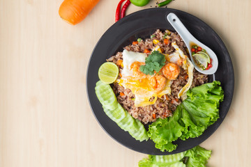 Fried brown rice with shrimp and fried egg in Thai. Prepared and served in a work, Low calories, Healthy food, Top view.