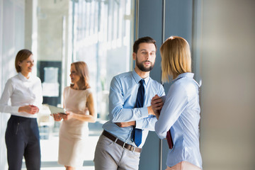 Business colleagues standing talking while leaning in office window