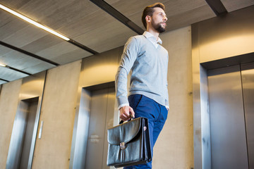 Young businessman walking while carrying briefcase bag