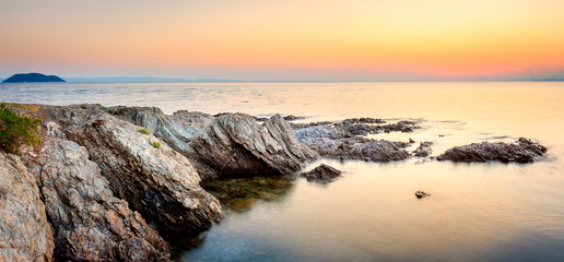 Obraz premium Panoramic view of narrow reef on Paradisos beach in Neos Marmaras and Turtle island during golden hour