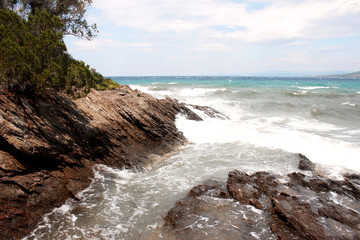Waves and white foam on the sea near the rocky reef on Paradisos beach in Neos Marmaras