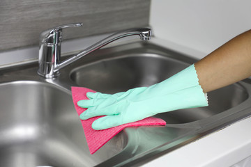 Hands in protective gloves with rag wiping sink. Maid or housewife cleans house. General cleaning...