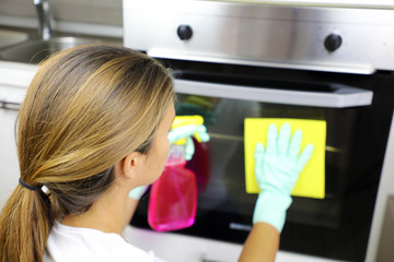 Fototapeta na wymiar Close up of woman with protective gloves cleaning oven door. Girl polishing kitchen. People, housework, cleaning concept.
