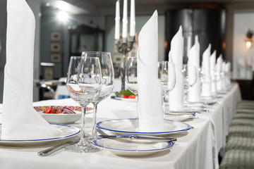 Table at a luxury wedding reception. Beautiful flowers on the table. Serving dishes, glass glasses, waiters work,