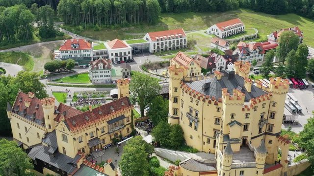 Aerial view of Hohenschwangau Castle in summer, picturesque palace in Bavarian Alps mountains, lush green hills - landscape panorama of Bavaria from above, Germany, Europe