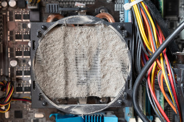 Old computer system unit cooler with dust inside. Dust on the computer pc processor cooler with computer case fragment.