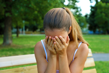 Bullying, discrimination or stress concept. Sad teenager crying alone in the park. Upset young...