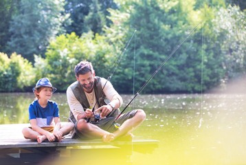 Father and son fishing in Lake while sitting on pier