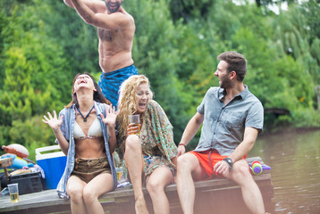 Cheerful couples enjoying on pier at lakeshore during summer