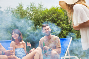 Woman preparing food in barbecue grill with friends on pier