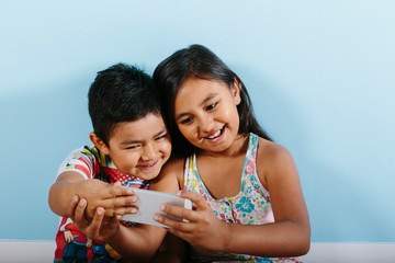 Two kids taking a selfie over blue background