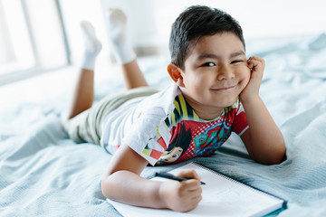 Kid lying on bed looking at camera.