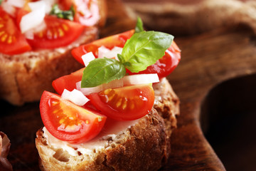 Tasty savory tomato Italian appetizers, or bruschetta on slices of toasted baguette garnished with basil