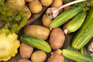 Squash, cucumbers, potatoes, dill, garlic lie on a brown wooden background, close-up