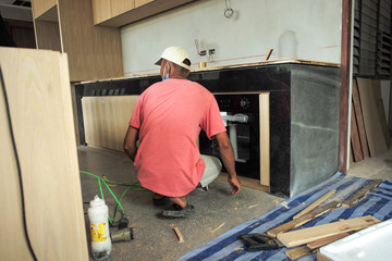 Back portrait of worker installs the oven into built-in furniture