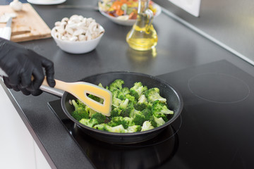 Chef cooked broccoli in frying pan on stove.