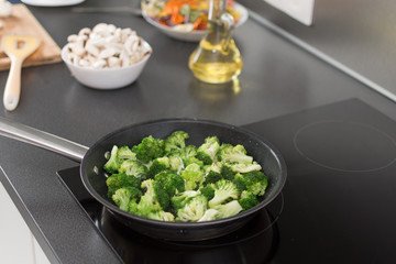 Cooked broccoli in frying pan on stove.