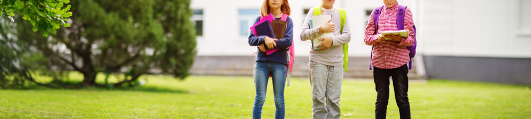 Children with rucksacks standing in the park near school