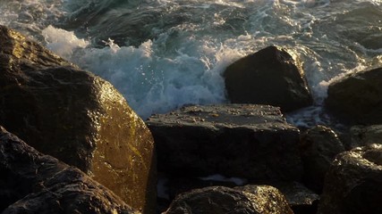 Sea waves crashing on stone beach.