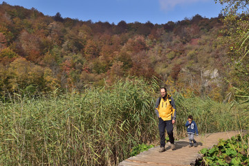 Obraz premium Boy and his father traveling together, hiking in Plitvice National Park, Croatia, in the fall