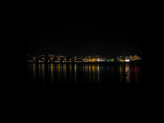 Wonderful night city landscape. Night city lights reflected in the water. The nightlife of the city in its remote manifestations.