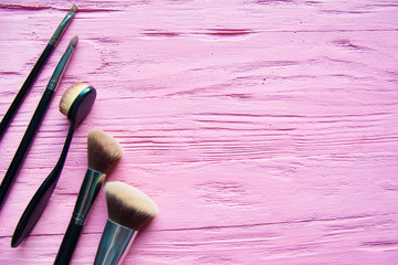 makeup brushes on pink textured wooden background