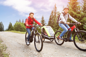 Family With Child In Trailer Riding Mountain Bikes