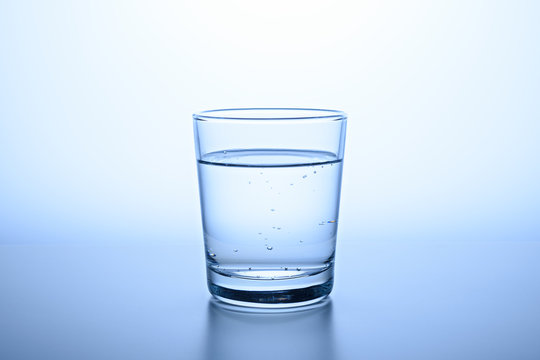 glass of clear water on blue background