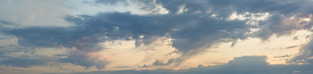 Fototapeta na wymiar Panorama of the cloudy sky illuminated by the rays of the setting sun