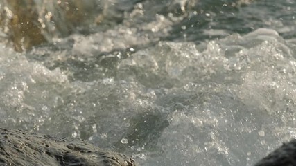 Sea waves crashing on stone beach.