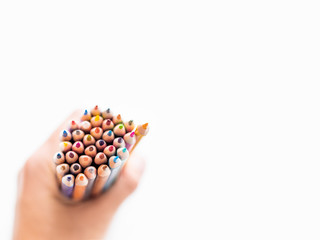 hand with bunch of colorful  pencils on white background. School supplies. Kid's stationery with copy space. Back to school backdrop.