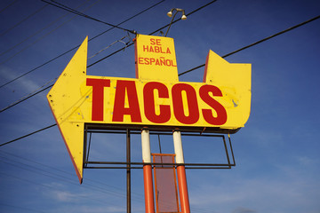 Aged and worn tacos sign with arrow