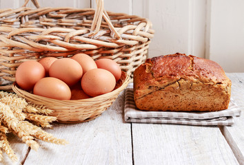 Loaf of bread, eggs in wicker basket and bunch of catkins.