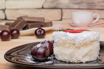 White cake with coconut flakes and sweet cherries