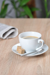 A cup of coffee and a newspaper on a table in a cafe. Light background. Free space for text.