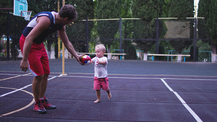 Obraz premium Athletic father and his little son playing on basketball playground.