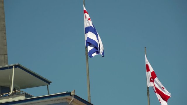 the American flag of Georgia and the national flag of Georgia are developing in the wind on a Sunny day.