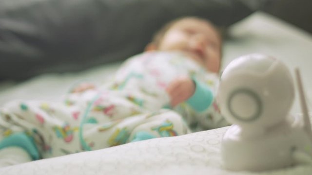 Slow motion from a baby monitor towards baby lying in bed