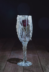 Glass decorated with streaks of wax with a small dry rose inside. Stylized drinks for Halloween