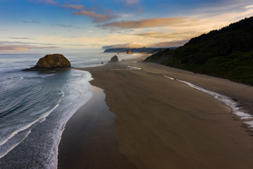 Sunrise View of Cannon Beach, Oregon. Beautiful morning light illuminates the white sand beaches and the Pacific Ocean along the stunning Oregon coastline during the summer season. 