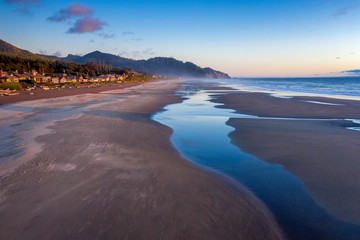 Aerial View of Arch Cape, Oregon. Sunset along the Oregon coast near Cannon Beach features white...
