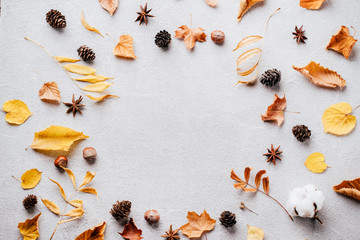 Autumn vibes. Pattern made of dried leaves and pine cones on concrete background. Seasonal background, fall concept, thanksgiving day composition. Flat lay, top view