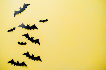 Halloween holiday concept. Funny paper bats decorations on bright yellow background. Party invitation mockup, celebration. Flat lay, top view, copy space