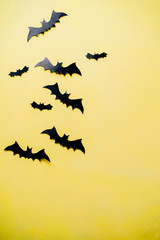 Halloween holiday concept. Funny paper bats decorations on bright yellow background. Party invitation mockup, celebration. Flat lay, top view, copy space