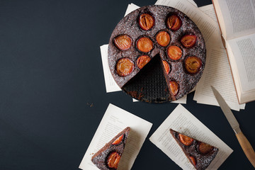 Plums tart with chocolate and slices on old pages