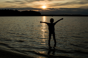 Sunset shadows. Shadows of children who are playing in the lake on the water in last sunshine.