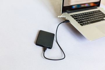 Black external hard disk connecting to a laptop
