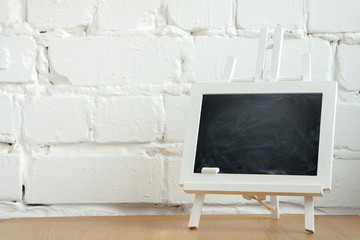 Close-up of a miniature chalk board with chalk stains and chalk on a white brick wall background, selective focus