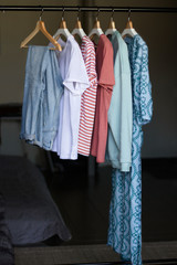 women's wardrobe in restrained shades of pink, blue and white hanging on the shoulders