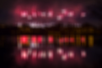 Abstract blurred color background with fireworks colored red lights over water and pond